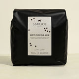 Black bag of Seahorse Hot Cocoa Mix on a beige background