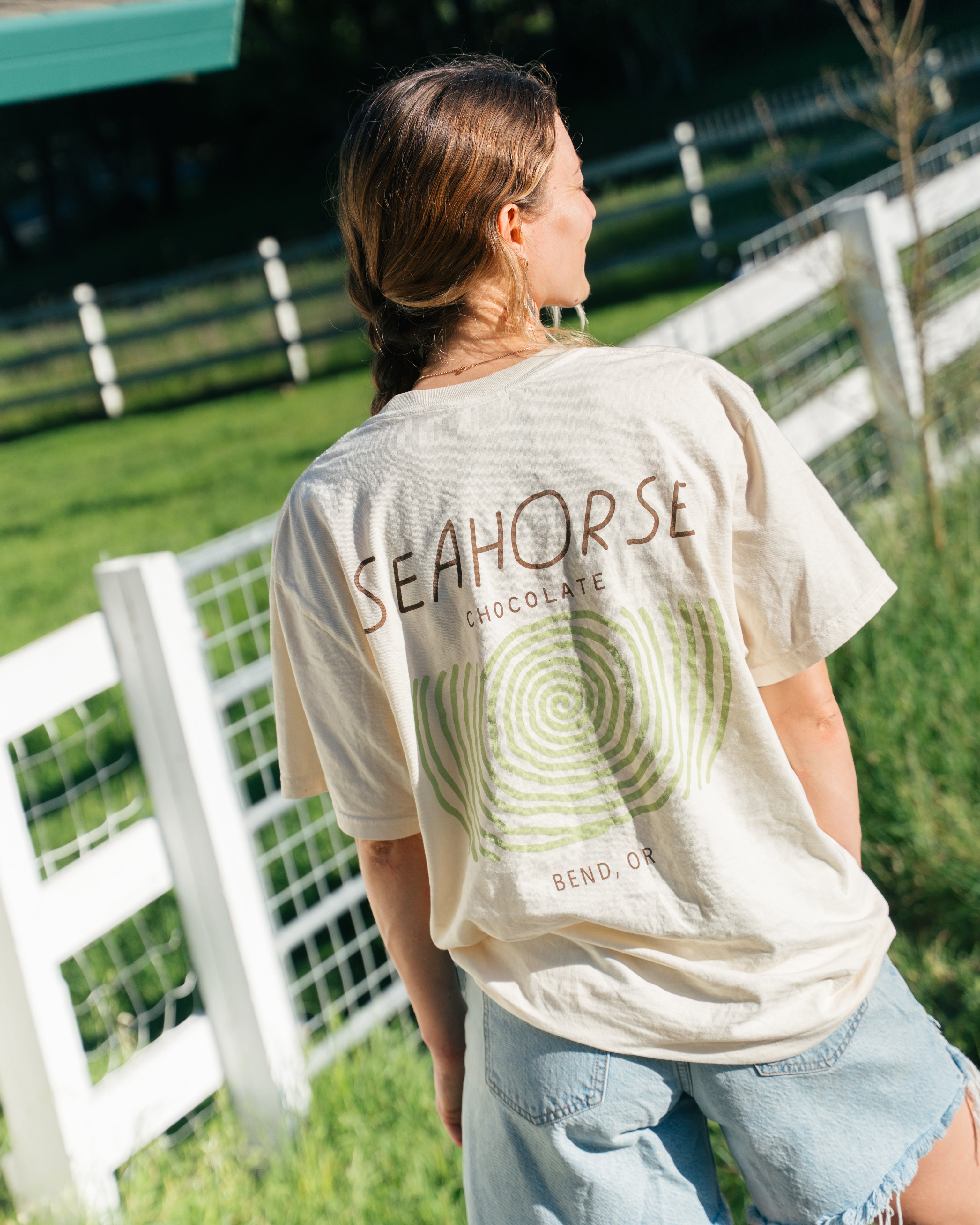 Beige cotton Seahorse classic tee with black wordmark logo on front, unisex fit worn outdoors