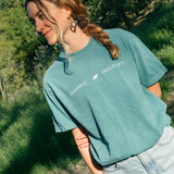 Sage blue cotton Seahorse classic tee with black wordmark logo on front, unisex fit worn outdoors