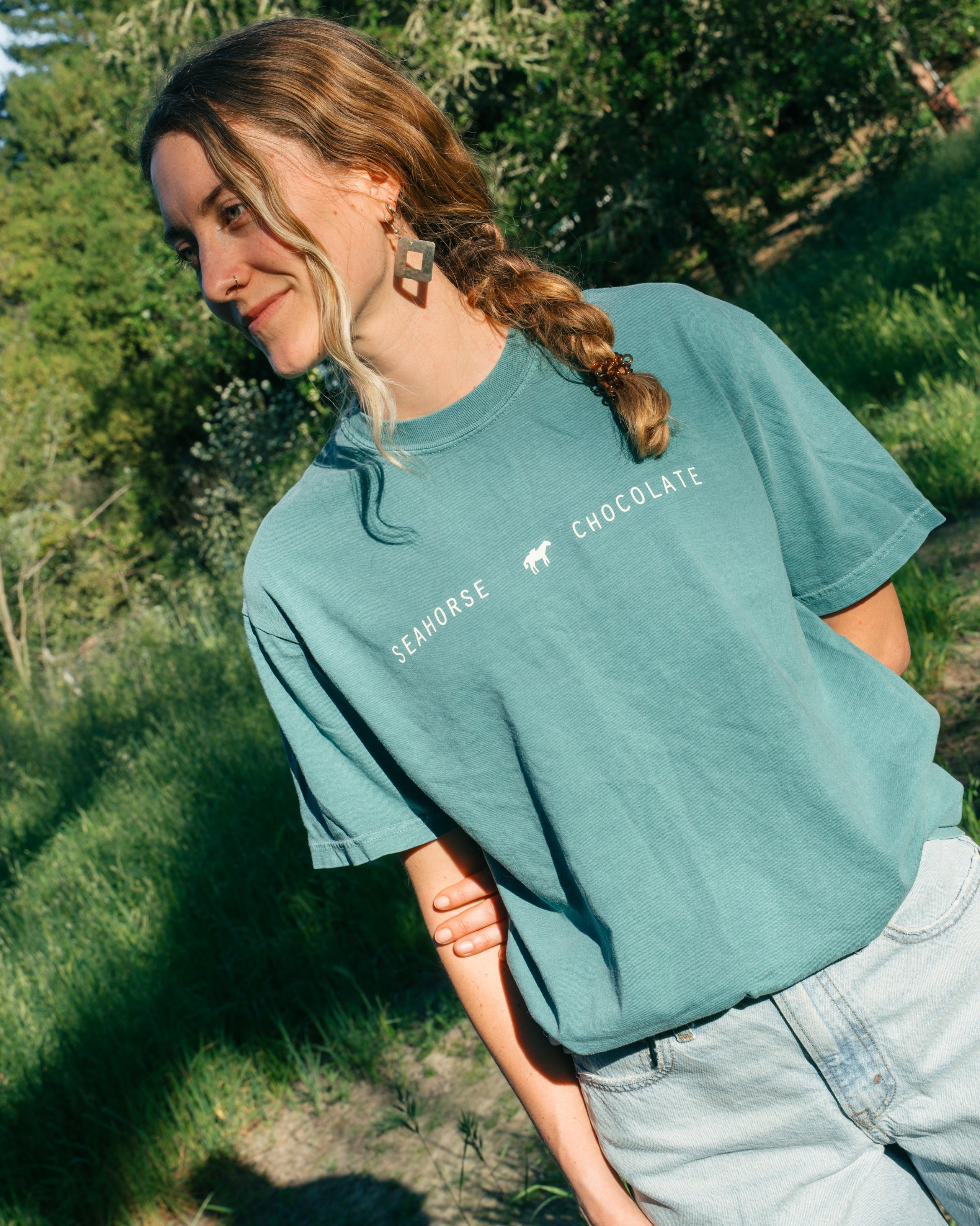 Sage blue cotton Seahorse classic tee with black wordmark logo on front, unisex fit worn outdoors